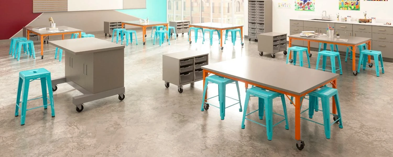 Classroom worktables with turquoise stools and storage cabinets